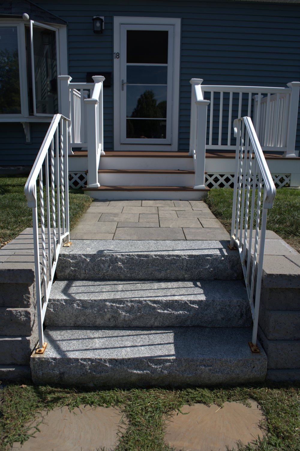 New paver walkway with granite steps and wrought-iron railings in front of a home