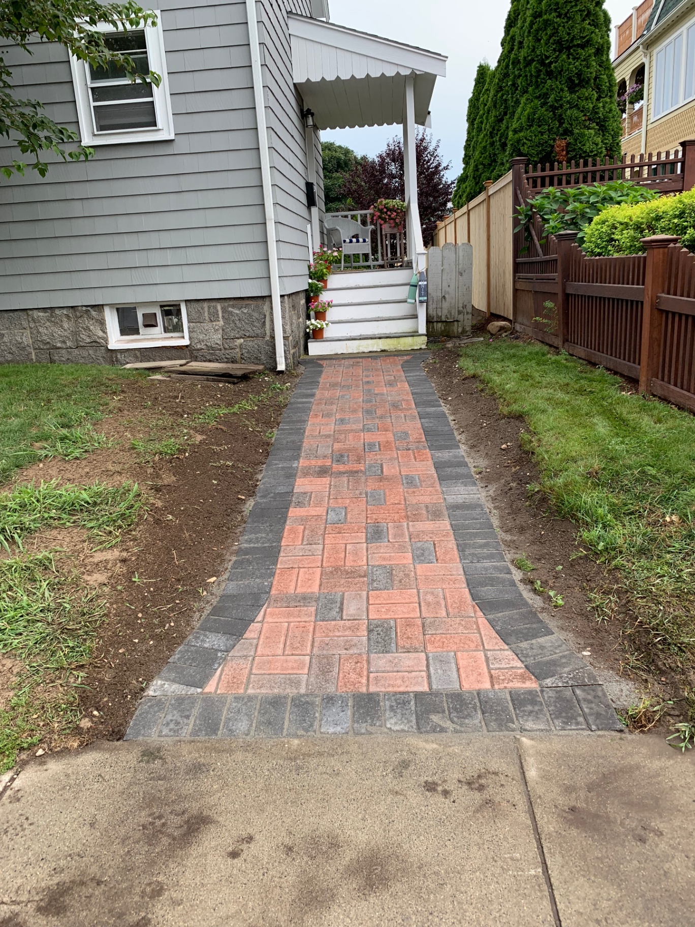 Red and charcoal brick paver walkway to a front porch