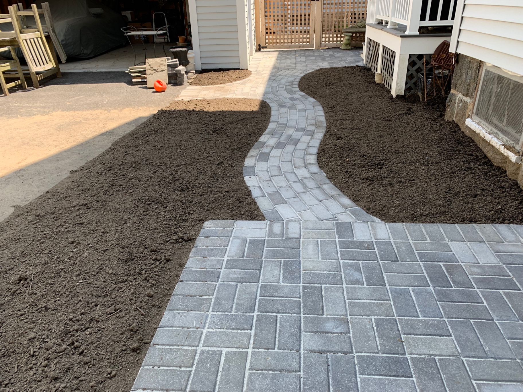 Winding gray paver walkway leading to a paver patio landing
